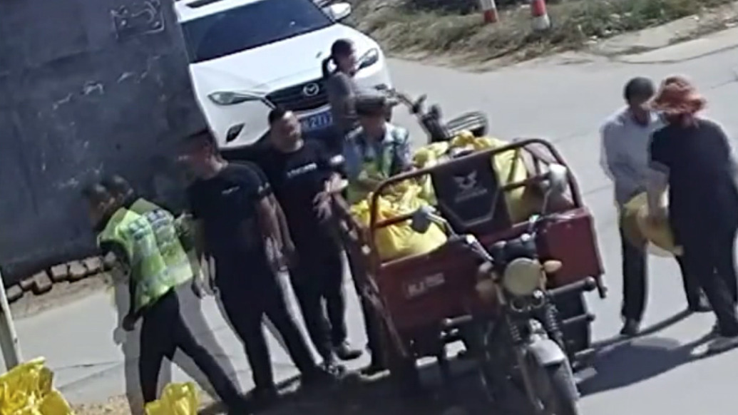 三轮车侧翻后玉米散落一地，附近交警、路人上前帮忙捡拾